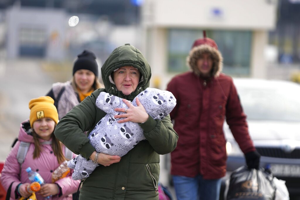 FILE - A Ukrainian family fleeing the Russian invasion arrives at the border crossing in Medyka, Poland, Wednesday, March 2, 2022, after fleeing from the Ukraine. The official global death toll from COVID-19 is on the verge of eclipsing 6 million — underscoring that the pandemic, now in its third year, is far from over. (AP Photo/Markus Schreiber, File)