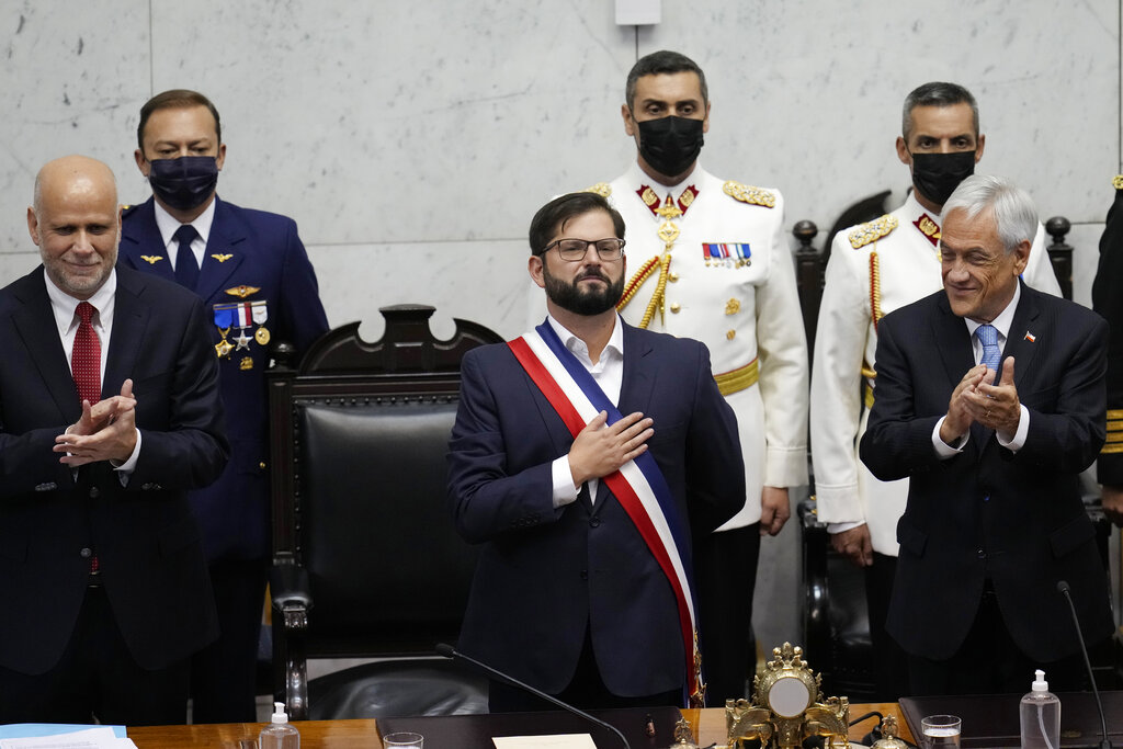 Chile's new President Gabriel Boric puts his hand on his chest as outgoing President Sebastian Pinera, right, applauds during his swearing-in ceremony at Congress in Valparaiso, Chile, Friday, March 11, 2022. (AP Photo/Esteban Felix)