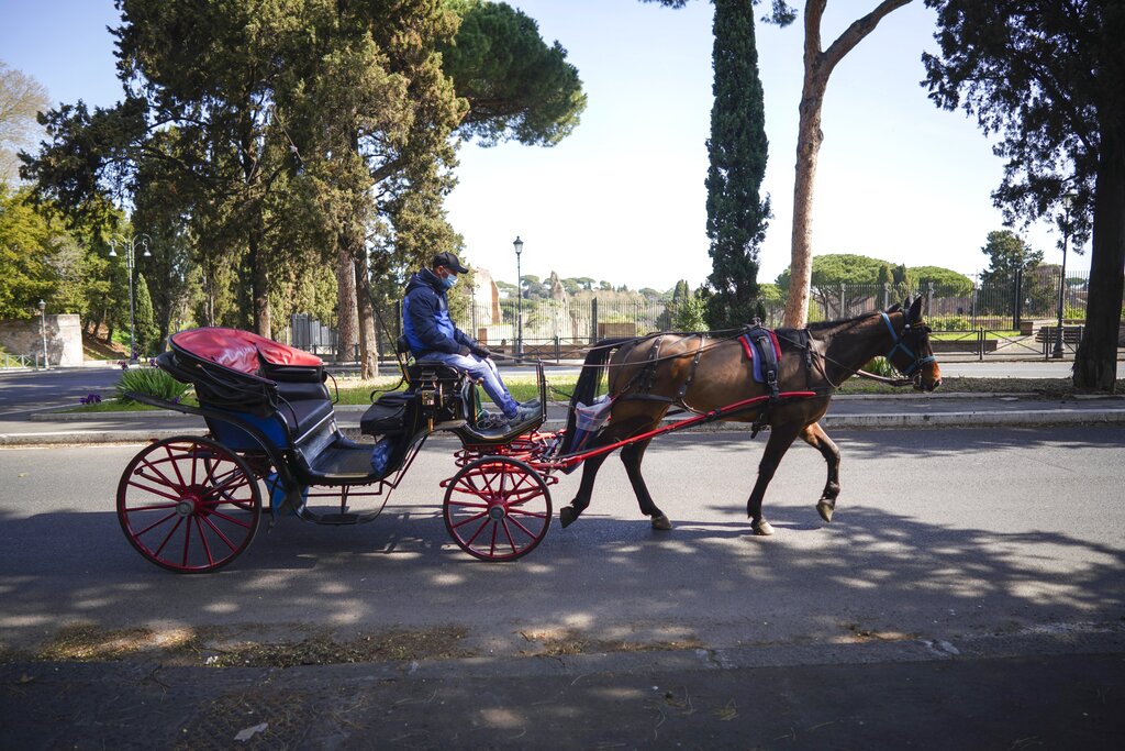 A traditional Roman horse carriage rides through the empty roads of Rome, Monday, March 23, 2020. For most people, the new coronavirus causes only mild or moderate symptoms. For some it can cause more severe illness, especially in older adults and people with existing health problems.(AP Photo/Andrew Medichini)