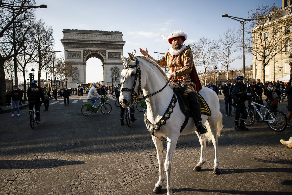 An actor dressed like King Henri IV rides a horse on the Champs-Elysees avenue to mark the end of the International Agricultural Fair, Sunday, March 6, 2022 in Paris. Animals and shepherds from a southwestern France region paraded on the famed avenue in a kind of transhumance to promote their work and their region. (AP Photo/Thomas Padilla)