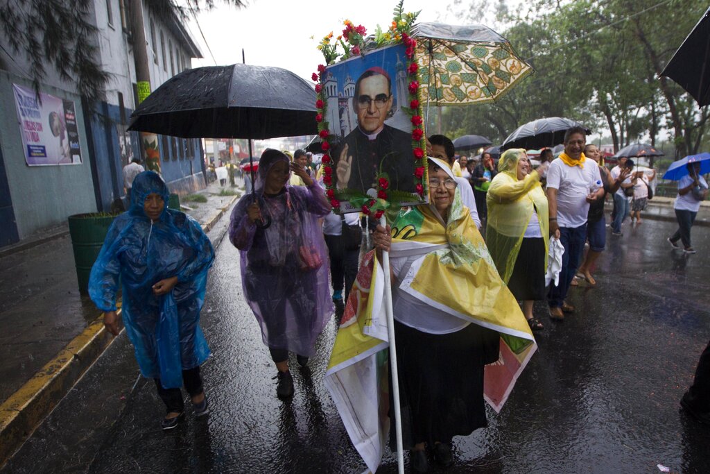 A woman walks with an image of Roman Catholic Archbishop Oscar Arnulfo Romero, during a march in San Salvador, El Salvador, Friday, May 22, 2015. Huge crowds are expected at a Saturday ceremony to beatify Romero, who was cut down by an assassin's bullet 35 years ago and declared a martyr for the faith this year by Pope Francis. (AP Photo/Moises Castillo)