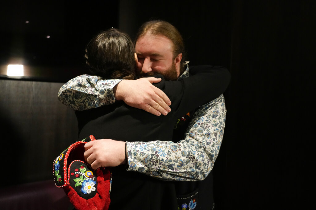 Mitchell Case, Community-based historian and educator and Region 4 Councillor, Metis Nation of Ontario, right, hugs the President of the Metis community, Cassidy Caron, who is wearing a traditional beaded jacket for her meeting with Pope Francis in Rome, Monday, March 28, 2022. A Canadian indigenous delegations is scheduled to have a week of meetings with Pope Francis at the Vatican. (AP Photo/Gregorio Borgia)