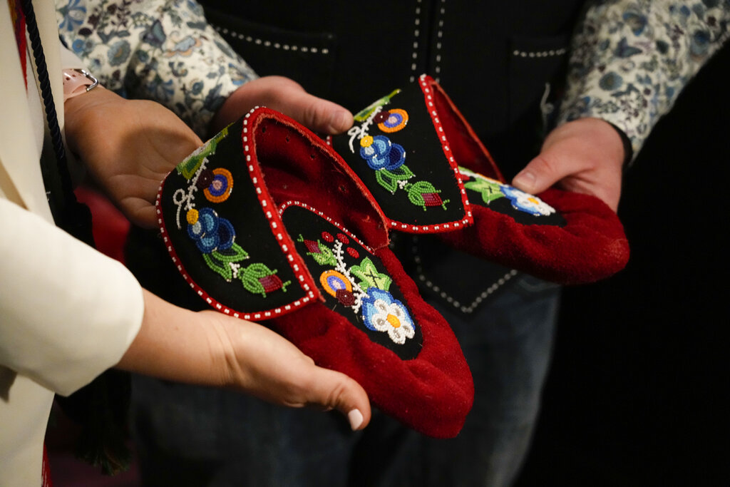 The President of the Metis community, Cassidy Caron and Mitchell Case, left, Community-based historian and educator and Region 4 Councillor, Metis Nation of Ontario, show to journalists a pair of traditional Metis pointed-toe style moccasin as a gift to Pope Francis in Rome, Monday, March 28, 2022. A Canadian indigenous delegations is scheduled to have a week of meetings with Pope Francis at the Vatican. (AP Photo/Gregorio Borgia)