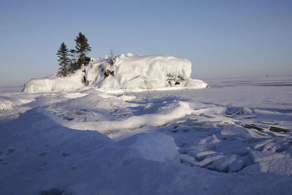 The sun begins to set over Hollow Rock on frozen Lake Superior in Grand Portage, Minn. on March 3, 2022. (AP Photo/Emma H. Tobin)
