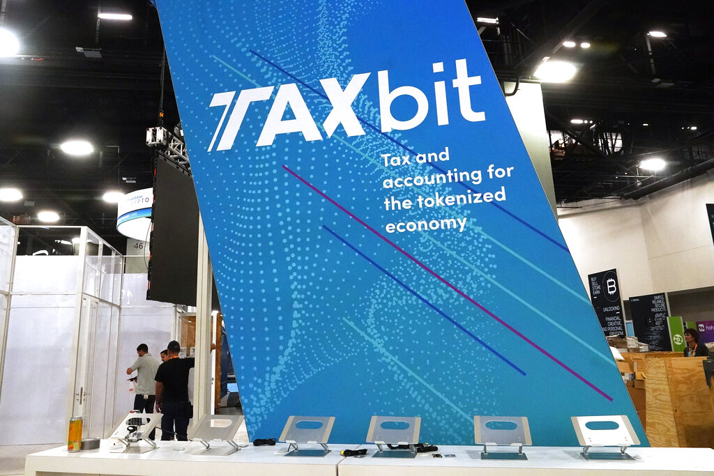 A tax and accounting firm sets up a booth at the Bitcoin 2022 conference at the Miami Beach Convention Center, Tuesday, April 5, 2022, in Miami Beach, Fla. Miami is gathering thousands of cryptocurrency enthusiasts as it positions itself as one of the hubs of blockchain technology. Dozens of companies are using the Bitcoin 2022 conference as a platform to pitch ideas to investors or share announcements to the crypto world and beyond. (AP Photo/Marta Lavandier)