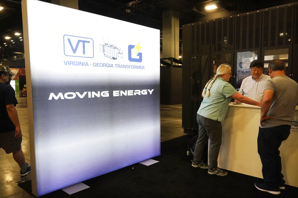 Employees for Virginia Georgia Transformer energy company set up their booth at the Miami Beach Convention Center, Tuesday, April 5, 2022, in Miami Beach, Fla. Miami is gathering thousands of cryptocurrency enthusiasts as it positions itself as one of the hubs of blockchain technology. Dozens of companies are using the Bitcoin 2022 conference as a platform to pitch ideas to investors or share announcements to the crypto world and beyond. (AP Photo/Marta Lavandier)