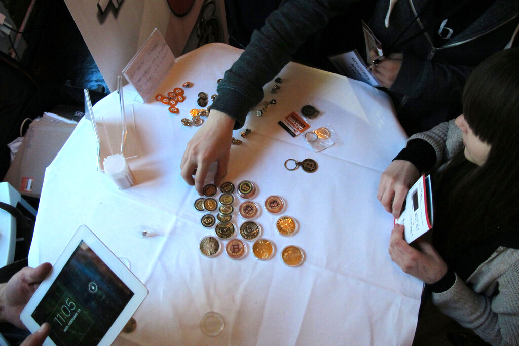 FILE - In this Feb. 12, 2014 file photo, attendees of the Inside Bitcoins conference in Berlin examine Bitcoin buttons. The website of major Bitcoin exchange Mt. Gox is offline amid reports it suffered a debilitating theft of the virtual currency, and the URL of the Tokyo-based outfit returns a blank page on Tuesday, Feb. 25, 2014. (AP Photo/Frank Jordans, File)