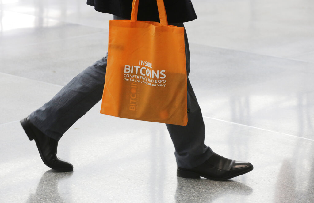 A person arrives for the Inside Bitcoins conference and trade show, Monday, April 7, 2014 in New York. Bitcoin users exchange cash for digital money using online exchanges, then store it in a computer program that serves as a wallet. The program can transfer payments directly to merchants or individuals around the world, eliminating transaction fees and the need for bank or credit card information. (AP Photo/Mark Lennihan)