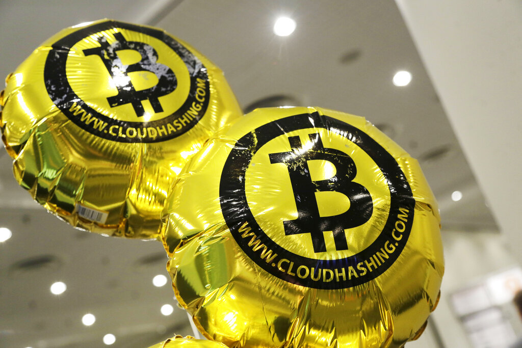 Balloons bearing the bitcoin logo float above the floor at the Inside Bitcoins conference and trade show, Monday, April 7, 2014 in New York. The balloons are part of a promotional effort by London-based Cloud Hashing, a bitcoin mining company. (AP Photo/Mark Lennihan)