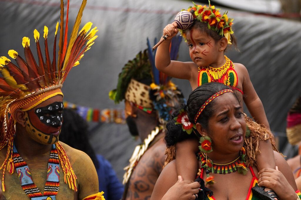 A Pataxo Indigenous couple and their child attend a ceremony called the Meeting of the First Peoples at the 18th annual Free Land Indigenous Camp in Brasilia, Brazil, Friday, April 8, 2022. The 10-day event aims to show the unity of Brazil's Indigenous peoples in their fight for the demarcation of their lands and their rights. (AP Photo/Eraldo Peres)