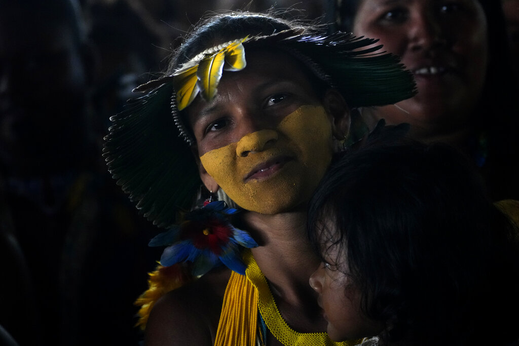 A Pataxo Indigenous woman and her daughter attend a ceremony called the Meeting of the First Peoples at the 18th annual Free Land Indigenous Camp in Brasilia, Brazil, Friday, April 8, 2022. The 10-day event aims to show the unity of Brazil's Indigenous peoples in their fight for the demarcation of their lands and their rights. (AP Photo/Eraldo Peres)
