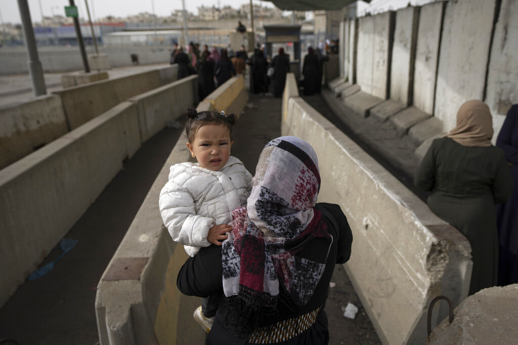 Palestinian families wait to cross from the West Bank into Jerusalem, for the first Friday prayers in the Muslim holy month of Ramadan at the Al Aqsa mosque compound, through the Qalandia Israeli army checkpoint, west of Ramallah, Friday, April 8, 2022. (AP Photo/Nasser Nasser)