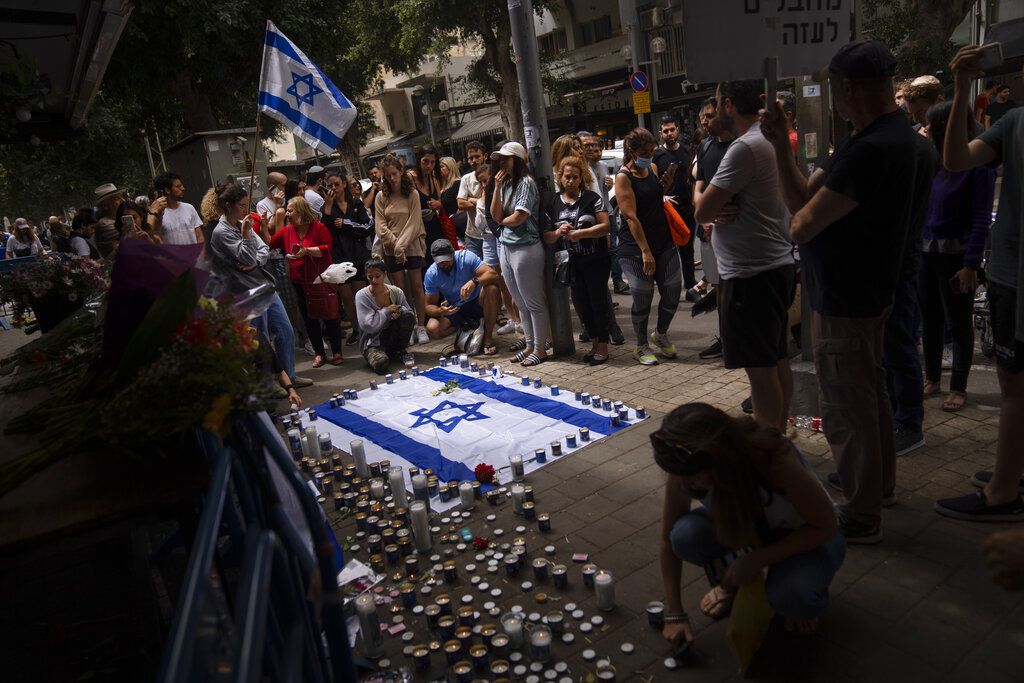 Israelis light candles at the site of last night shooting attack, in Tel Aviv, Israel, Friday, April 8, 2022. Israeli security forces early Friday hunted down and killed a Palestinian man who had opened fire into a crowded bar in central Tel Aviv, killing two and wounding over 10 in an attack that caused scenes of mass panic in the heart of the bustling city on Thursday night. (AP Photo/Oded Balilty)