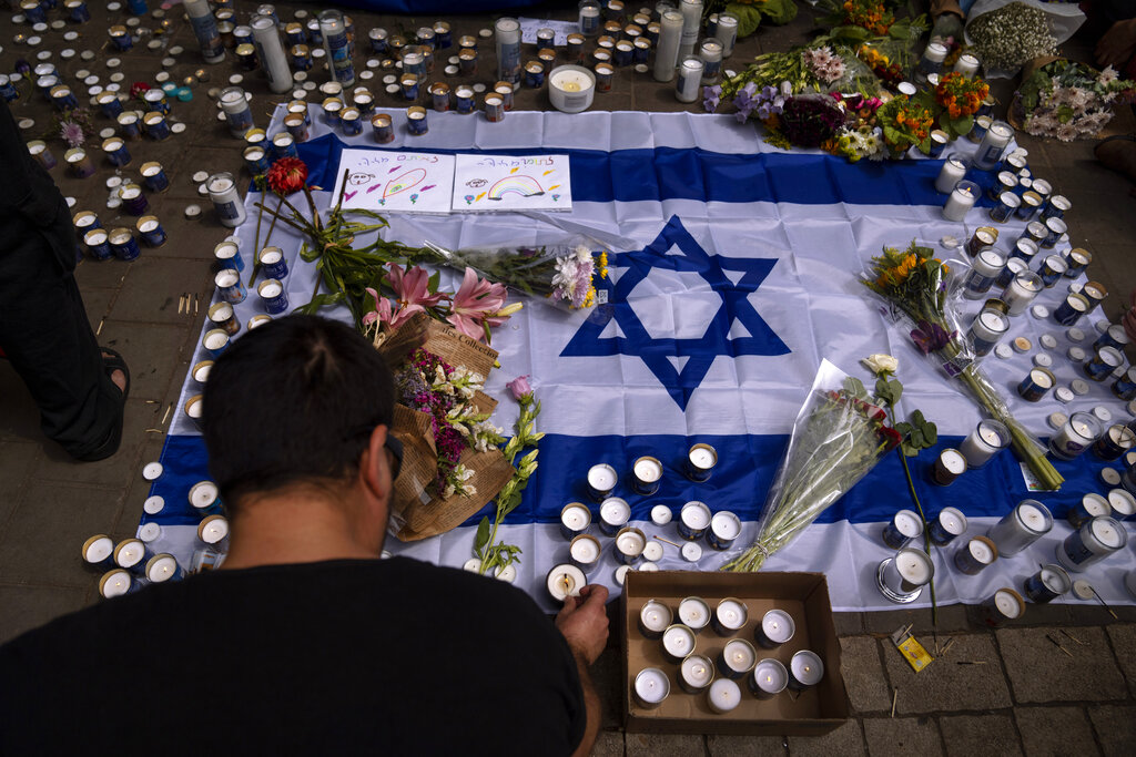 People light candles at the site of last night shooting attack, in Tel Aviv, Israel, Friday, April 8, 2022. Israeli security forces early Friday hunted down and killed a Palestinian man who had opened fire into a crowded bar in central Tel Aviv, killing two and wounding over 10 in an attack that caused scenes of mass panic in the heart of the bustling city on Thursday night. (AP Photo/Oded Balilty)