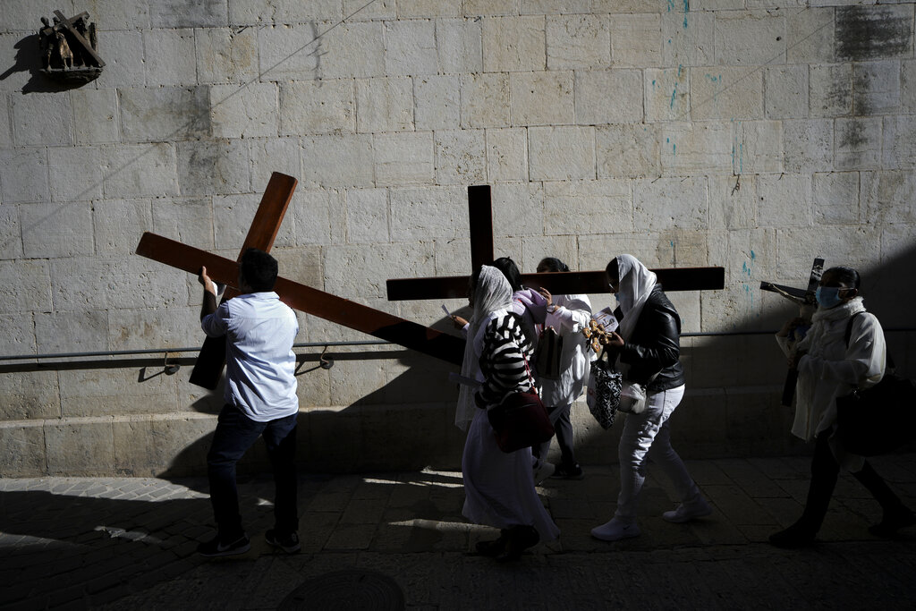 Christian worshippers carry cross as they walk along the Via Dolorosa towards the Church of the Holy Sepulchre, where many Christians believe Jesus was crucified, buried and rose from the dead, during the Good Friday procession in Jerusalem's Old City, Friday, April 15, 2022. (AP Photo/Ariel Schalit)