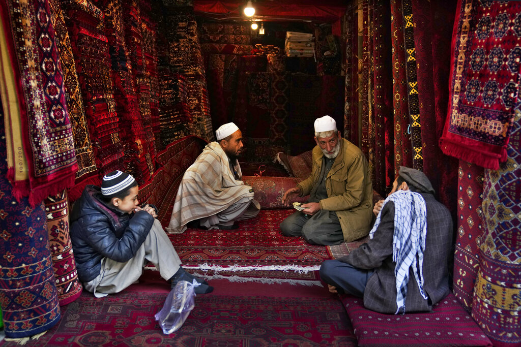 Carpet sellers make deals with each other at the carpet market in Kabul, Afghanistan, Monday, Feb. 21, 2022. (AP Photo/Hussein Malla)