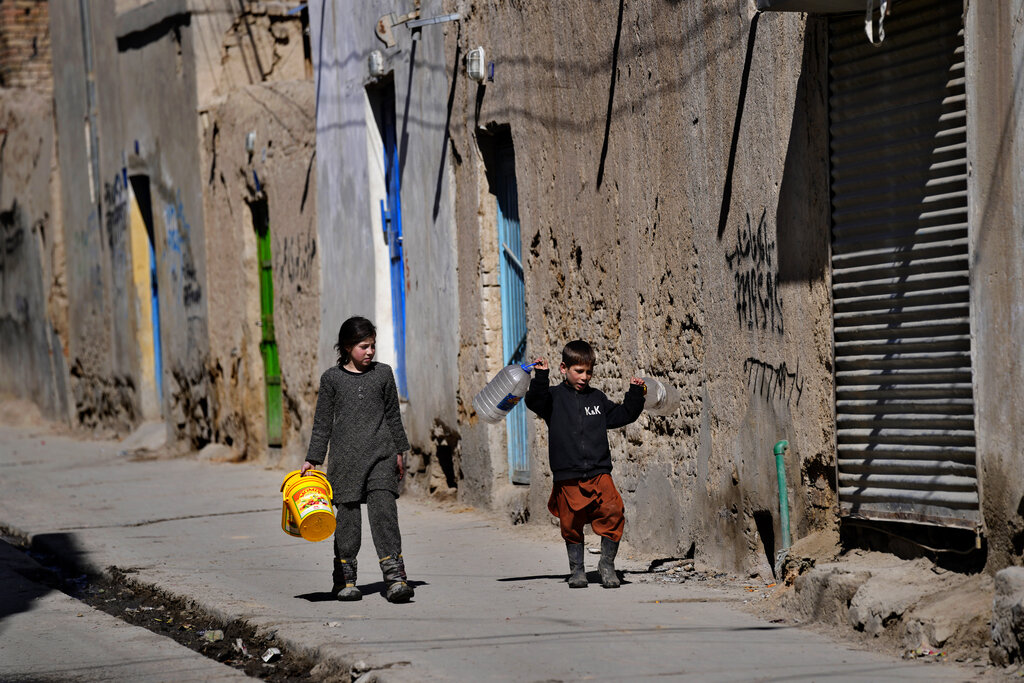 Afghan children carry empty containers as they go to fill them water from a well, in Kabul, Afghanistan, Sunday, Feb. 20, 2022. (AP Photo/Hussein Malla)