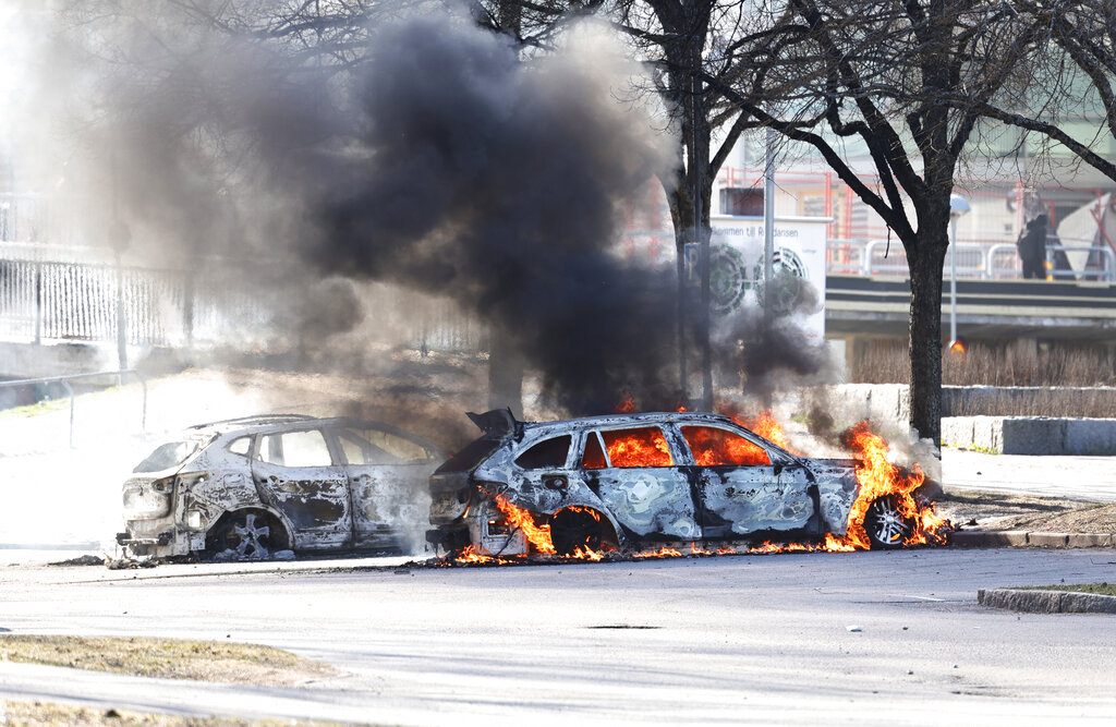 Two cars are burn in a parking lot during a riot in Norrkoping, Sweden, Sunday, April 17, 2022. Unrest has broken out in southern Sweden despite police moving a rally by an anti-Islam far-right group, which was planning to burn a Quran among other things, to a new location as a preventive measure.  (Stefan Jerrevang/TT News Agency via AP)