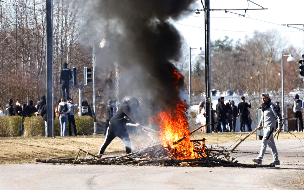 People burn branches to block a road during a riot in Norrkoping, Sweden, Sunday, April 17, 2022. Unrest has broken out in southern Sweden despite police moving a rally by an anti-Islam far-right group, which was planning to burn a Quran among other things, to a new location as a preventive measure.  (Stefan Jerrevang/TT News Agency via AP)