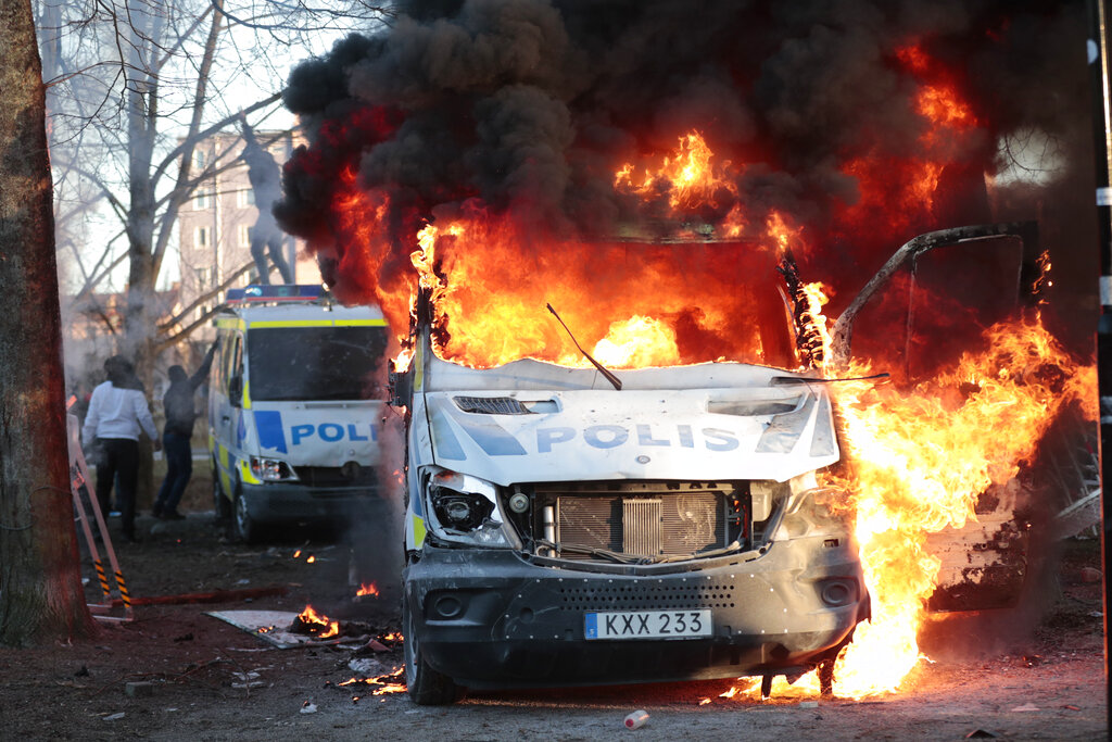 Protesters set fire to a police bus in the park Sveaparken in Orebro, Sweden, Friday, April 15, 2022. Police in Sweden say they are preparing for new violent clashes following riots that erupted between demonstrators and counter-protesters in the central city of Orebro on Friday ahead of an anti-Islam far-right group’s plan to burn a Quran there. (Kicki Nilsson/TT via AP)
