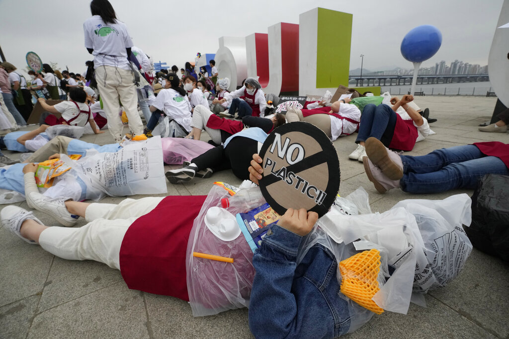 An environmental activist wearing a plastic bag lies down on the ground during a campaign to mark Earth Day against climate change in Seoul, South Korea, Friday, April 22, 2022. (AP Photo/Ahn Young-joon)