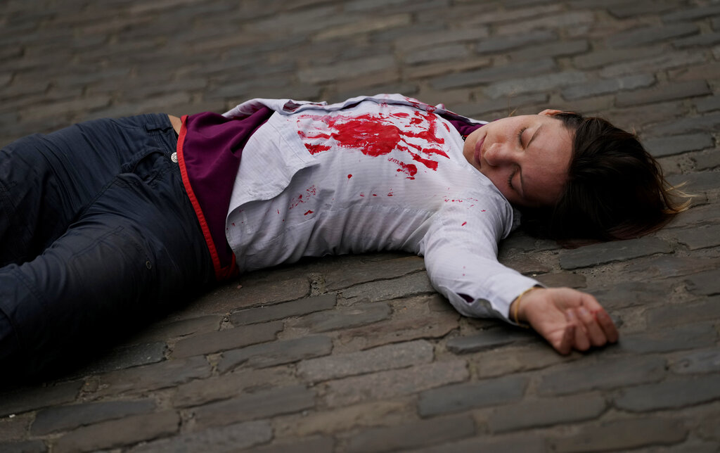 A protestor is splashed in red paint and lies on the pavement as she demonstrates on Earth Day in front of the German embassy in Brussels, Friday, April 22, 2022. Protestors demonstrated on Friday calling on governments to end fossil fuel projects involving Russian companies. (AP Photo/Virginia Mayo)