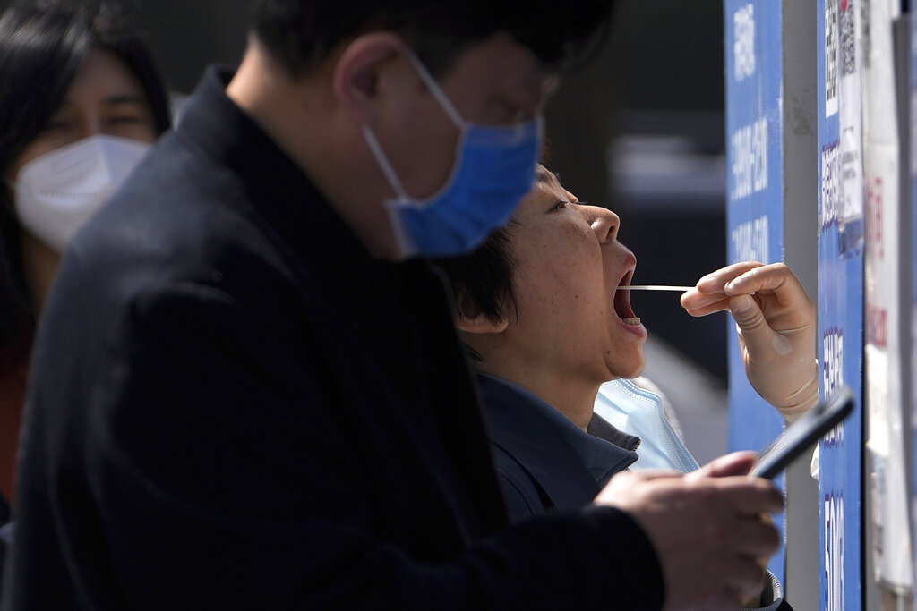 Residents line up to get their throat swab at a coronavirus testing site, Tuesday, April 5, 2022, in Beijing. China has sent more than 10,000 health workers from across the country to Shanghai, including 2,000 military medical staff, as it struggles to stamp out a rapidly spreading COVID-19 outbreak in China's largest city. (AP Photo/Andy Wong)