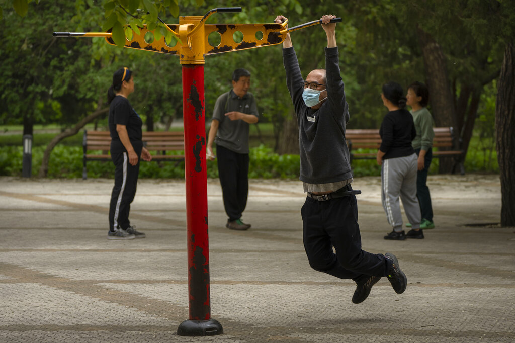 A man wearing a face mask exercises at a public park in Beijing, Thursday, April 21, 2022. In mainland China, the death toll rose to more than 20 in an outbreak in Shanghai that has all but shut down the country's largest city. (AP Photo/Mark Schiefelbein)