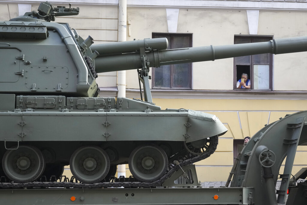 A woman looks at a self-propelled artillery vehicle Msta-S transported by trucks prior to a rehearsal for the Victory Day military parade which will take place at Dvortsovaya (Palace) Square on May 9 to celebrate 77 years after the victory in World War II in St. Petersburg, Russia, Thursday, April 28, 2022. (AP Photo/Dmitri Lovetsky)