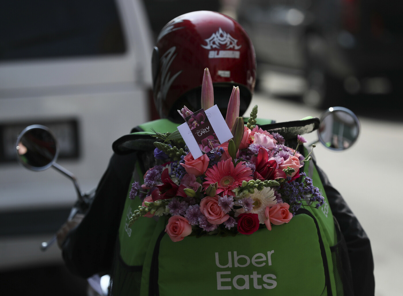 An Uber worker carries a bouquet of flowers to be delivered during mothers’ day in Mexico City, Sunday, May 10, 2020. (AP Photo/Fernando Llano)