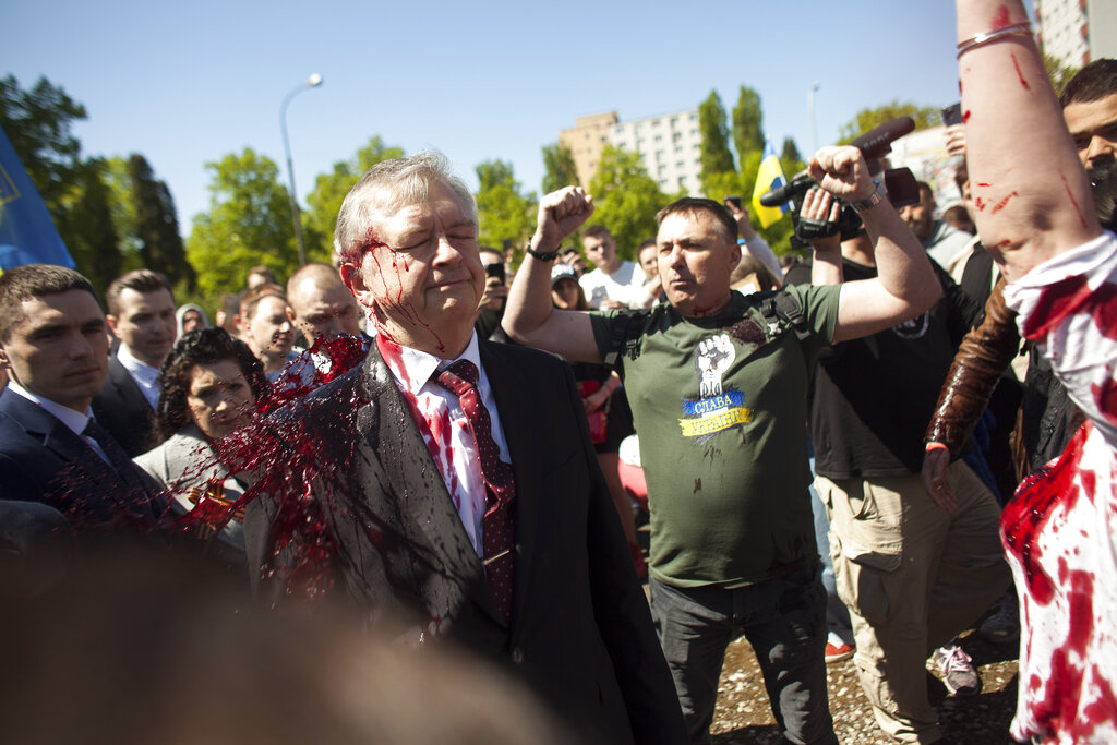 Activists hold up their arms as Russian Ambassador to Poland, Ambassador Sergey Andreev is covered with red paint in Warsaw, Poland, Monday, May 9, 2022. Protesters have thrown red paint on the Russian ambassador as he arrived at a cemetery in Warsaw to pay respects to Red Army soldiers who died during World War II. Ambassador Sergey Andreev arrived at the Soviet soldiers cemetery on Monday to lay flowers where a group of activists opposed to Russia’s war in Ukraine were waiting for him. (AP Photo/Maciek Luczniewski)