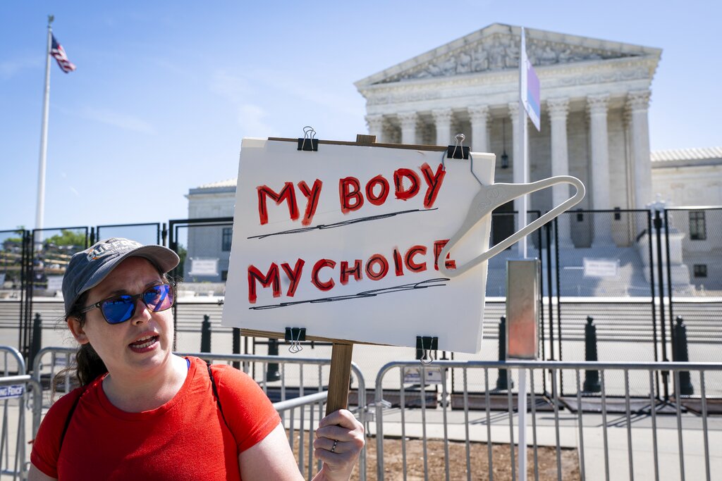 Michelle Peterson, of Silver Spring, Md., protests outside of the Supreme Court, Tuesday, May 10, 2022, which is lined with anti-scaling fencing in Washington. 