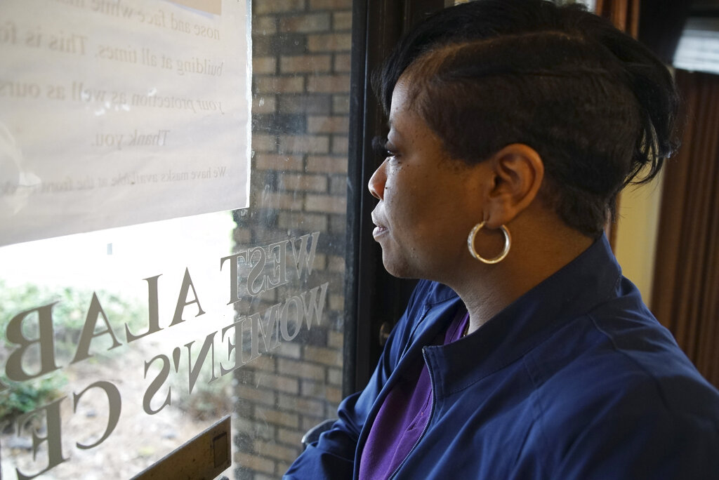 Alesia Horton, director of the West Alabama Women's Center in Tuscaloosa, Ala., looks out the window at protesters on Tuesday, March 15, 2022. A deeply religious woman, she says of those who picket the clinic: 