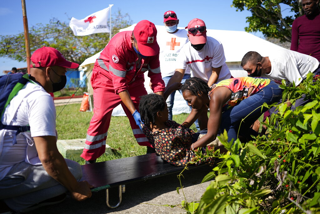 Cuban Red Cross workers help a Haitian migrant onto a stretcher at a tourist campground in Sierra Morena, in the Villa Clara province of Cuba, Wednesday, May 25, 2022. A vessel carrying more than 800 Haitians trying to reach the United States wound up instead on the coast of central Cuba, government news media said Wednesday. (AP Photo Ramon Espinosa)