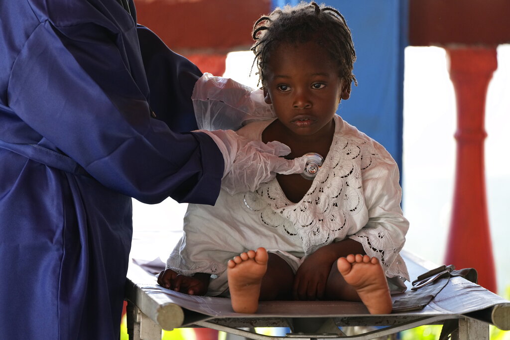 A healthcare worker examines a Haitian migrant child at a tourist campground in Sierra Morena, in the Villa Clara province of Cuba, Wednesday, May 25, 2022. A vessel carrying more than 800 Haitians trying to reach the United States wound up instead on the coast of central Cuba, government news media said Wednesday. (AP Photo Ramon Espinosa)