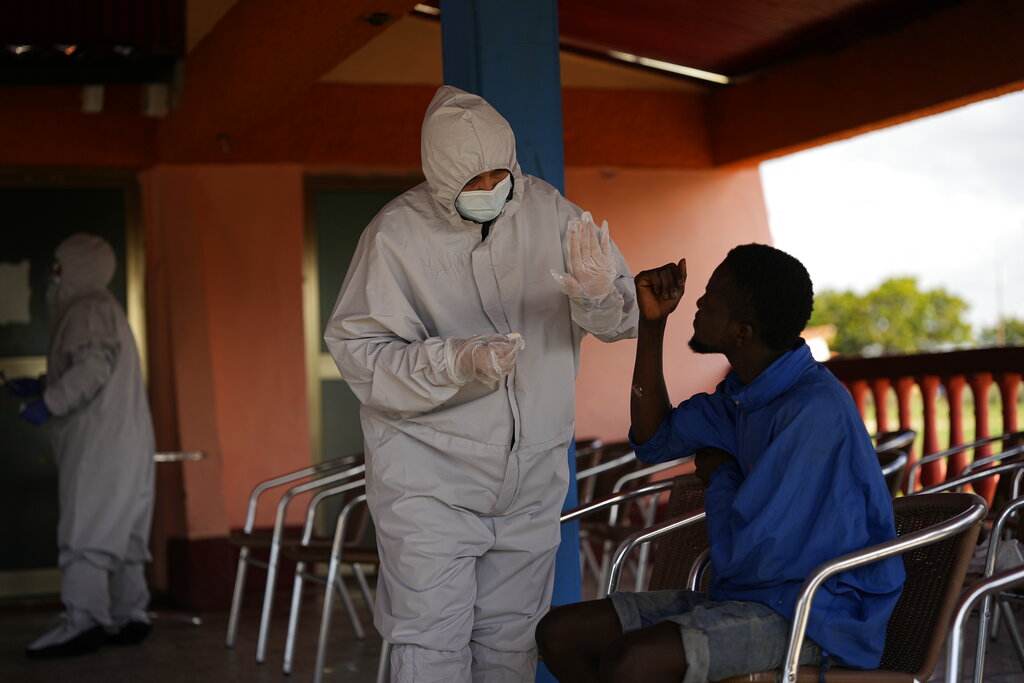 A healthcare worker greets a Haitian migrant at a tourist campground in Sierra Morena, in the Villa Clara province of Cuba, Wednesday, May 25, 2022. A vessel carrying more than 800 Haitians trying to reach the United States wound up instead on the coast of central Cuba, government news media said Wednesday. (AP Photo Ramon Espinosa)