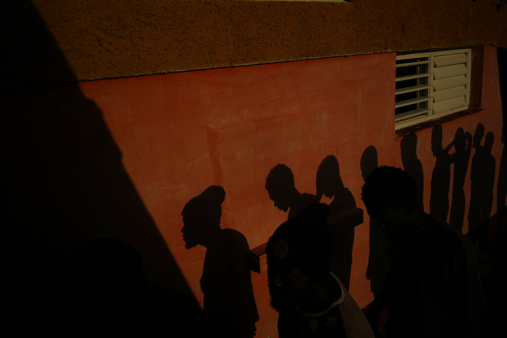 The shadows of Haitian migrants are cast on a wall as they wait to receive food at a tourist campground in Sierra Morena, in the Villa Clara province of Cuba, Wednesday, May 25, 2022. A vessel carrying more than 800 Haitians trying to reach the United States wound up instead on the coast of central Cuba, government news media said Wednesday. (AP Photo Ramon Espinosa)