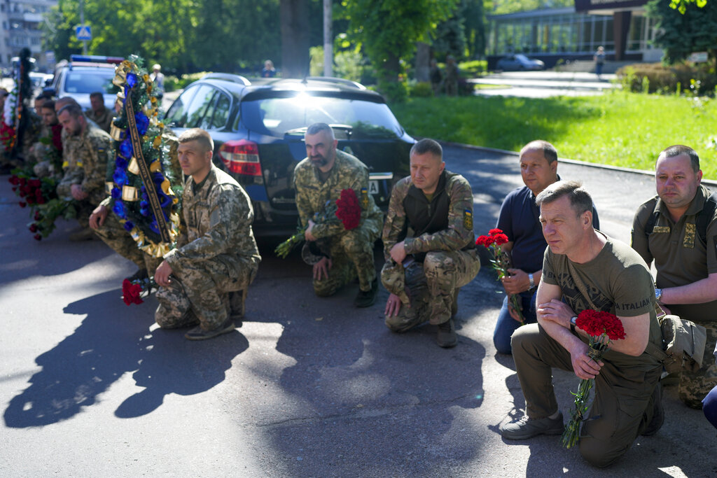 Ukrainian service men kneel during the a funeral service for Army Col. Oleksander Makhachek in Zhytomyr, Ukraine, Friday, June 3, 2022. According to combat comrades Makhachek was killed fighting Russian forces when a shell landed in his position on May 30. (AP Photo/Natacha Pisarenko)