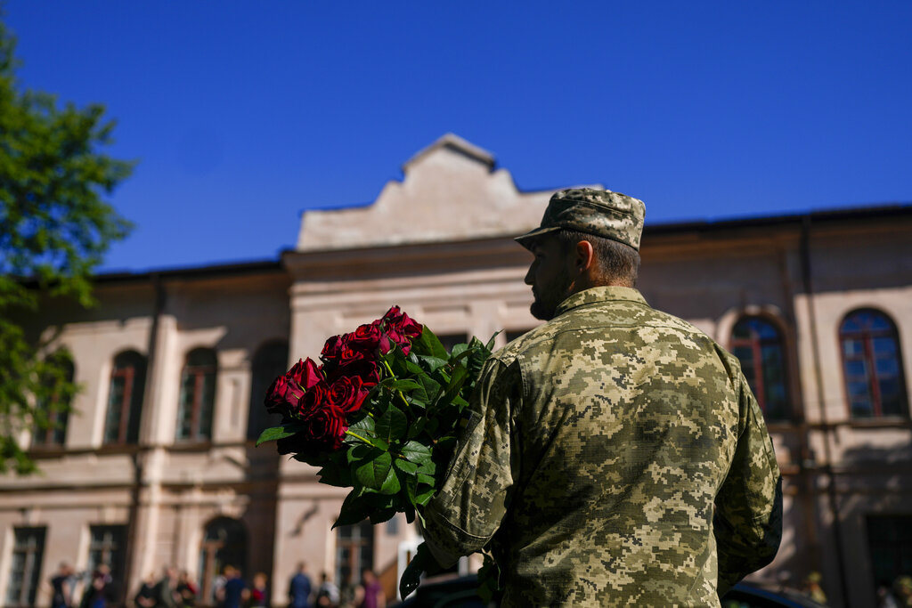 An Ukrainian serviceman holds flowers during the a funeral service for Army Col. Oleksander Makhachek in Zhytomyr, Ukraine, Friday, June 3, 2022. According to combat comrades Makhachek was killed fighting Russian forces when a shell landed in his position on May 30. (AP Photo/Natacha Pisarenko)