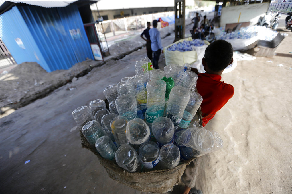 An Indian worker carries used plastic bottles for recycling, at a railway station on World Environment Day in Ahmadabad, India, Tuesday, June 5, 2018. The U.N. says government bans on plastic can be effective in cutting back on waste but poor planning and follow-through have left many such bans ineffective. (AP Photo/Ajit Solanki)