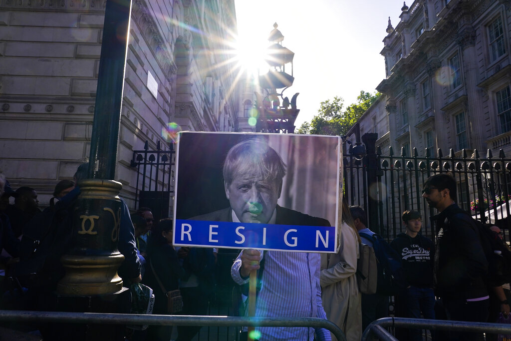 A demonstrator holds a placard depicting Britain's Prime Minister Boris Johnson while attending a workers protest outside the gates of Downing Street, in London, Friday, May 27, 2022. An investigative report released Wednesday blamed British Prime Minister Boris Johnson and other senior leaders for allowing boozy government parties that broke the U.K.'s COVID-19 lockdown rules, and while Johnson said he took 