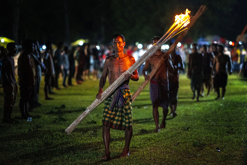 Indian Rabha tribal Hindu priests head to perform rituals before burning wood during Baikho festival at Gamerimura village along the Assam Meghalaya border, west of Gauhati, India, Saturday, June 4, 2022. Every year, the community in India's northeastern state of Assam celebrates the festival, to please a deity of wealth and ask for good rains and a good harvest. (AP Photo/Anupam Nath)