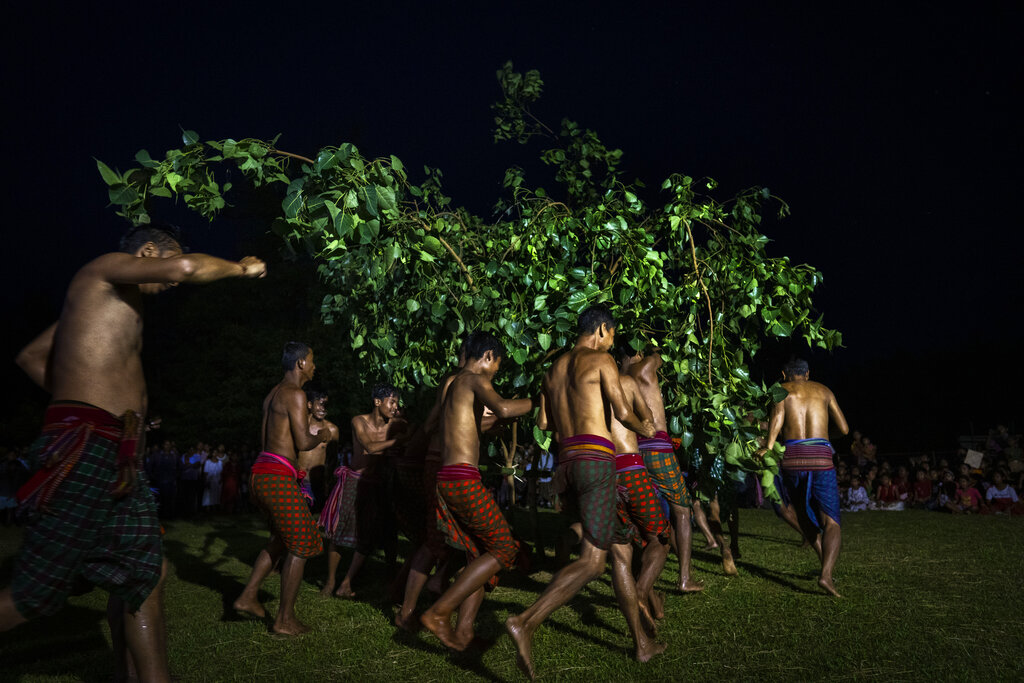Indian Rabha tribal Hindu priests walk around tree branches as they perform rituals during Baikho festival at Gamerimura village along the Assam Meghalaya border, west of Gauhati, India, Saturday, June 4, 2022. Every year, the community in India's northeastern state of Assam celebrates the festival, to please a deity of wealth and ask for good rains and a good harvest. (AP Photo/Anupam Nath)