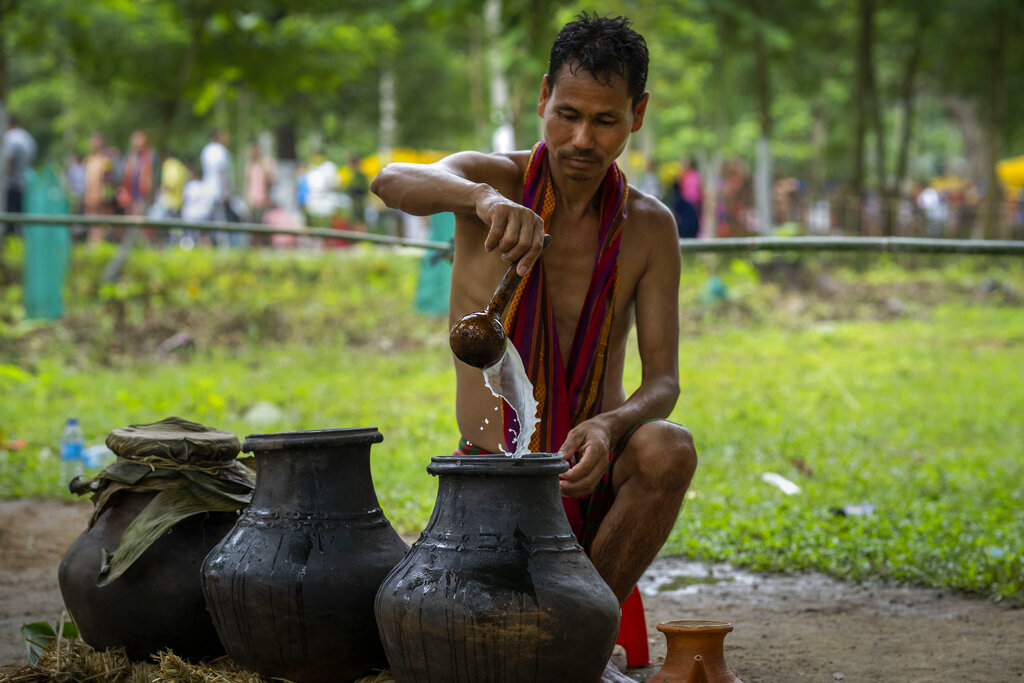 An Indian Rabha tribal Hindu priest prepares rice beer in earthen pots which will be served to the Rabha people as holy water during Baikho festival at Gamerimura village along the Assam Meghalaya border, west of Gauhati, India, Saturday, June 4, 2022. Every year, the community in India's northeastern state of Assam celebrates the festival, to please a deity of wealth and ask for good rains and a good harvest. (AP Photo/Anupam Nath)