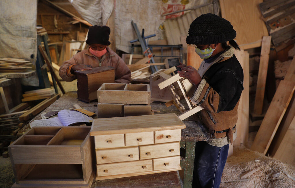 Wearing masks to curb the spread of the new coronavirus, the Delgado children work in the family's carpentry workshop in El Alto, Bolivia, Friday, Aug. 28, 2020. The Bolivian government decided to cancel the school year in August because it said there was no way to provide an equitable education to the country's nearly 3 million students, which put more kids to work. (AP Photo/Juan Karita)