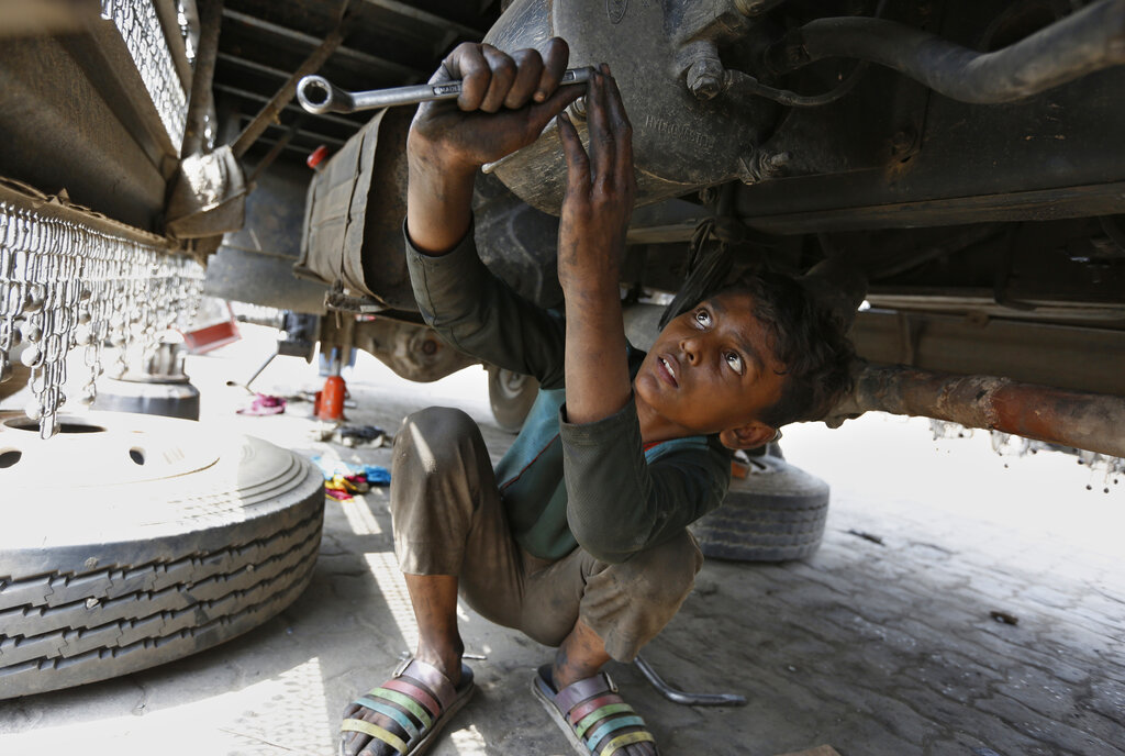 Sami Ullah, 10 years old, works at an automotive repair shop to earn living for his family in Lahore, Pakistan, Saturday, June 12, 2021. The International Labor Organization (ILO) observes June 12 as the World Day Against Child Labor to highlight the plight of child laborers. (AP Photo/K.M. Chaudary)