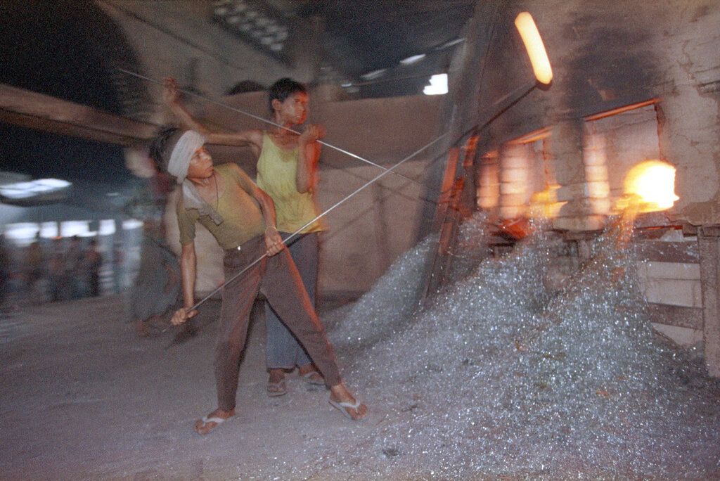 Boys pull molten glass out of a fiery furnace at a glass factory in Firozabad, India, June 26, 1993. The children, some as young as 6, work 10-hour days in the 122 degree heat for about $1. While critics say the children work in subhuman conditions and miss an education, others note that in India, where one in three people don't earn enough money for more than one meal a day, hunger takes priority. (AP Photo/John Moore)