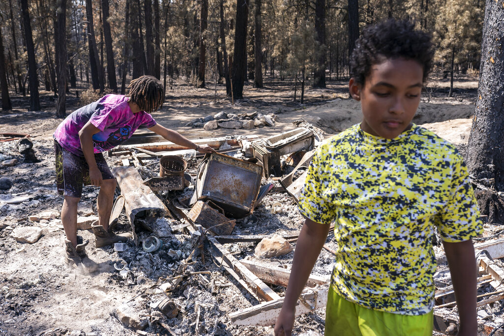 FILE - Sayyid Bey, left, and his son Nicolas Bey, 11, sift through the remains of their burnt home on July 22, 2021, after it was destroyed by the Bootleg Fire near Bly, Ore. Climate change and an enduring drought have fanned the frequency and intensity of wildfires in the West in recent years. (AP Photo/Nathan Howard, File)