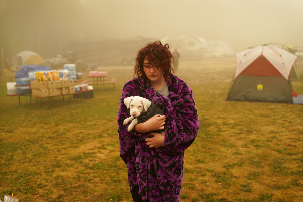 FILE - Shayanne Summers holds her dog, Toph, after several days of staying in a tent at an evacuation center at the Elks Lodge, in Oak Grove, Ore., Sept. 13, 2020. Climate change and an enduring drought have fanned the frequency and intensity of wildfires in the West in recent years. (AP Photo/John Locher, File)