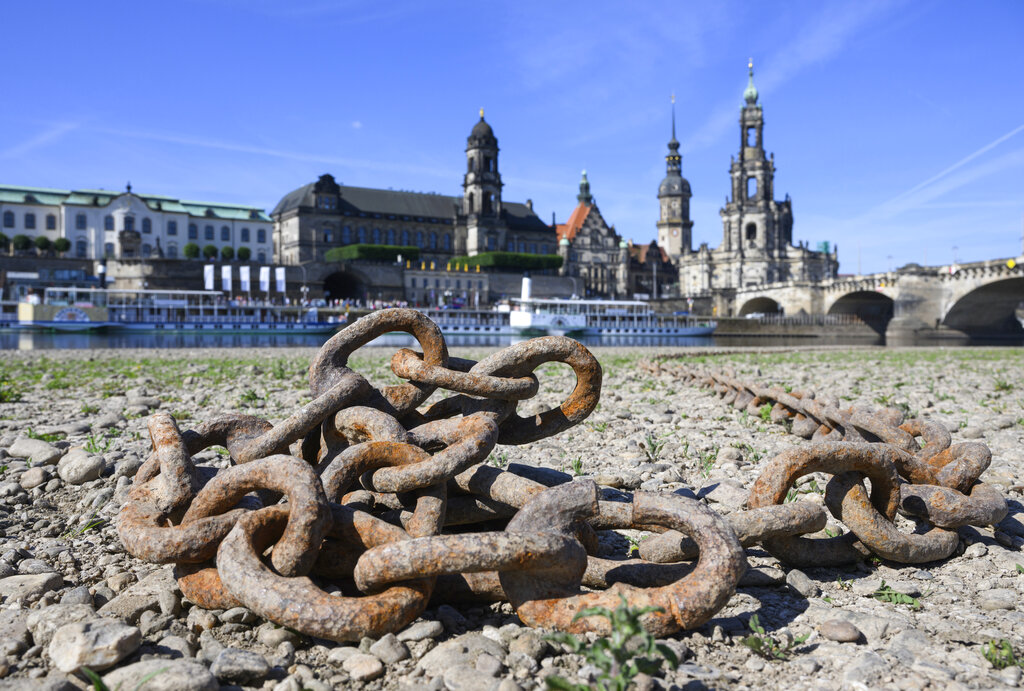A rusted chain lies on the dried-up bank of the Elbe in front of the Old Townin Dresden, Germany, Friday, June 17, 2022. The level of the Elbe in Dresden is currently 93 centimeters. Shortly before the calendrical beginning of summer, the first heat wave is approaching Germany. The peak is expected to be reached on Saturday, 18.06.2022 with temperatures up to 38 degrees. (Robert Michael/dpa via AP)